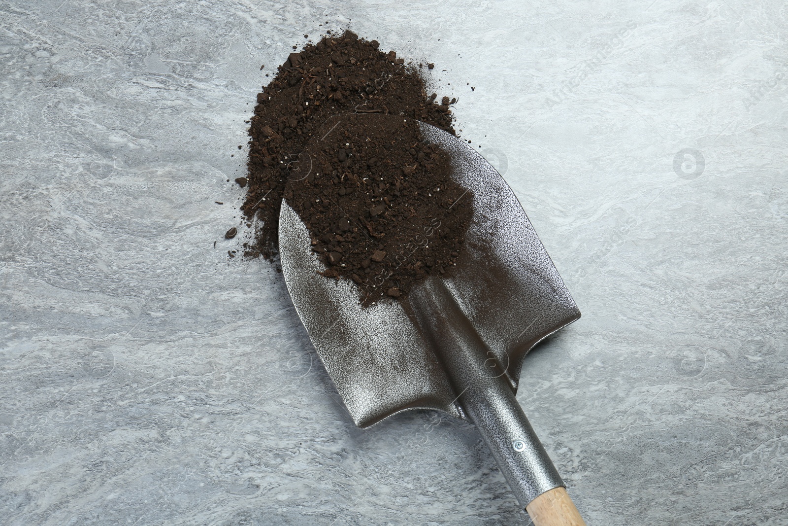 Metal shovel with fertile soil on gray textured surface, top view Photo of Metal shovel with fertile soil on gray textured surface, top view