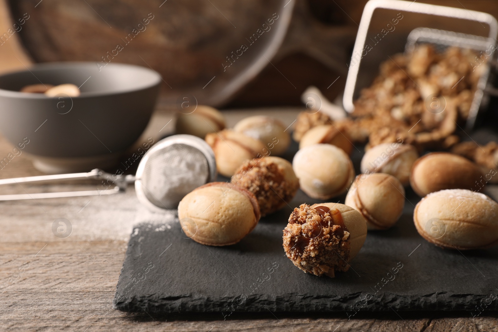 Photo of Freshly baked homemade walnut shaped cookies and flour on wooden table, closeup