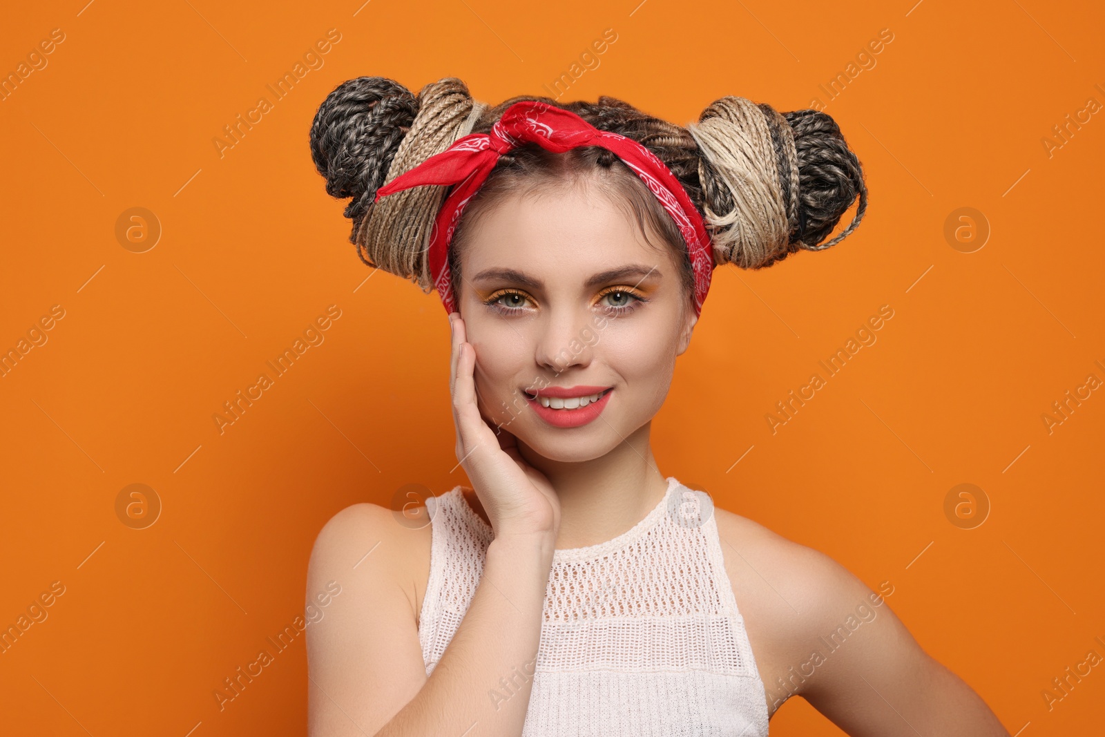 Photo of Beautiful woman with braided double buns on orange background