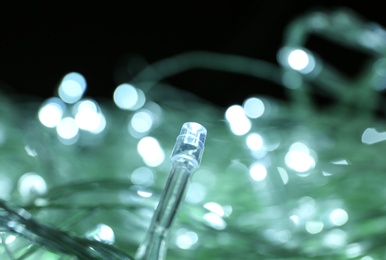 Photo of Glowing Christmas lights on green background, closeup