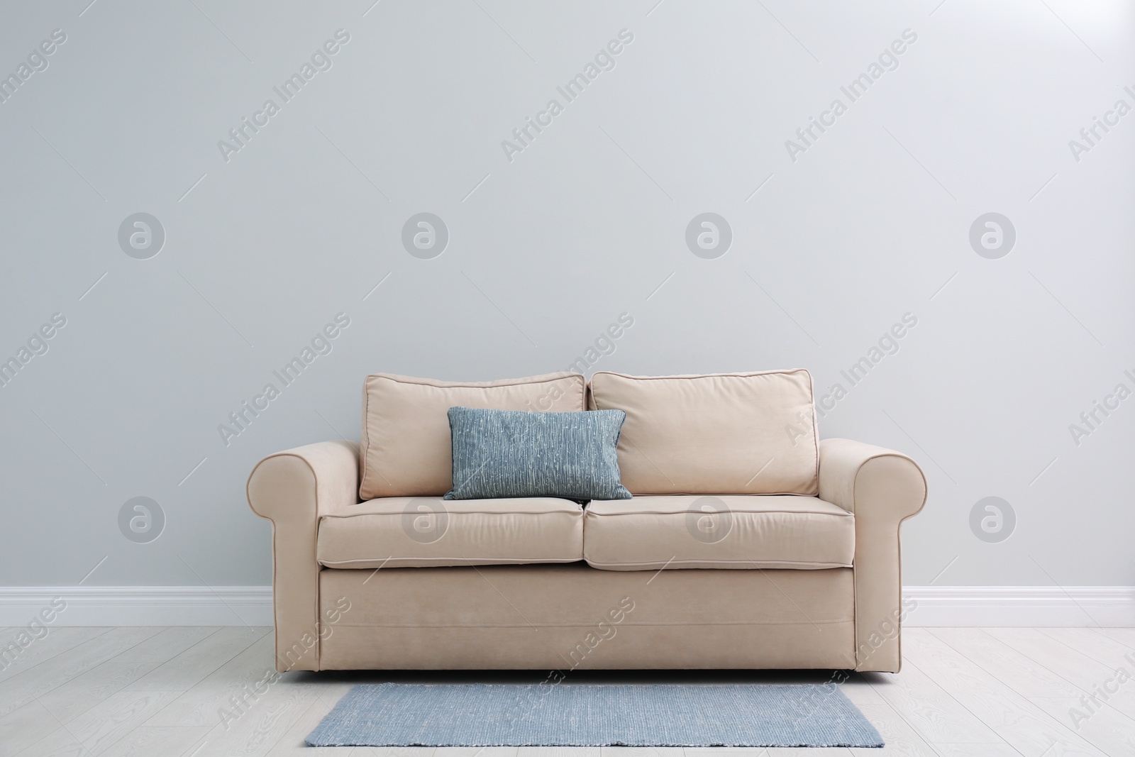 Photo of Comfortable beige sofa near light wall indoors, space for text. Simple interior