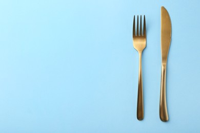 Photo of Stylish cutlery on light blue table, top view. Space for text