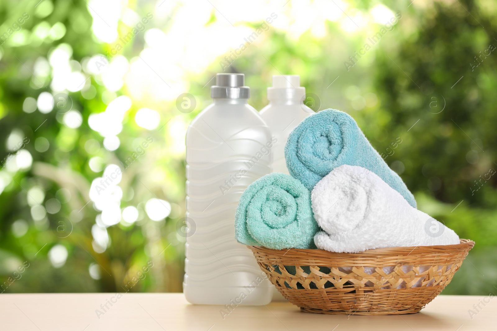 Photo of Soft bath towels and laundry detergents on table against blurred background. Space for text