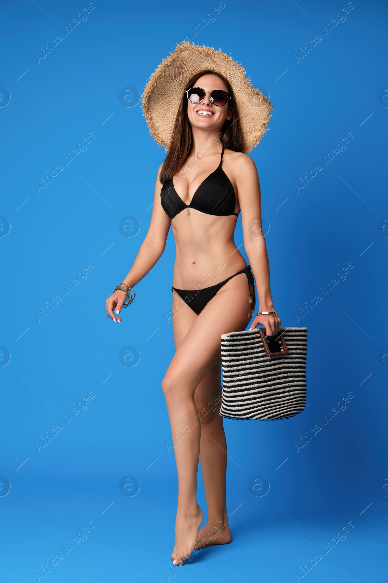 Photo of Pretty sexy woman with slim body in stylish  black bikini on blue background