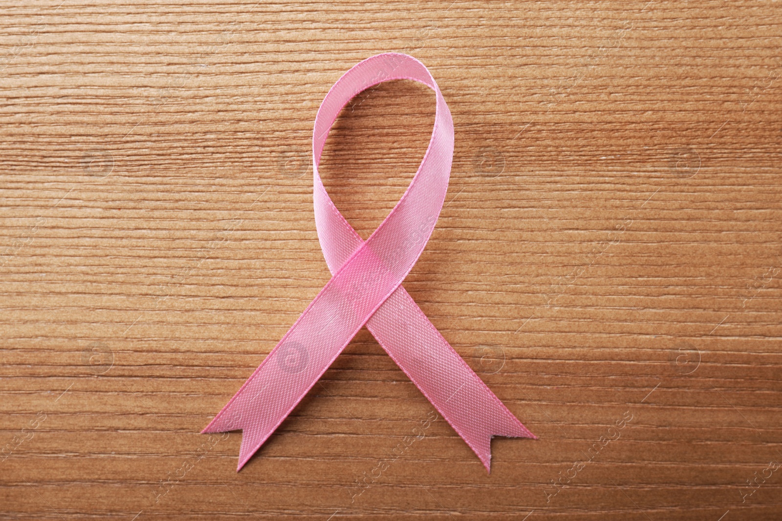 Photo of Pink ribbon on wooden background, top view. Breast cancer awareness concept