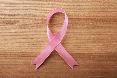 Pink ribbon on wooden background, top view. Breast cancer awareness concept