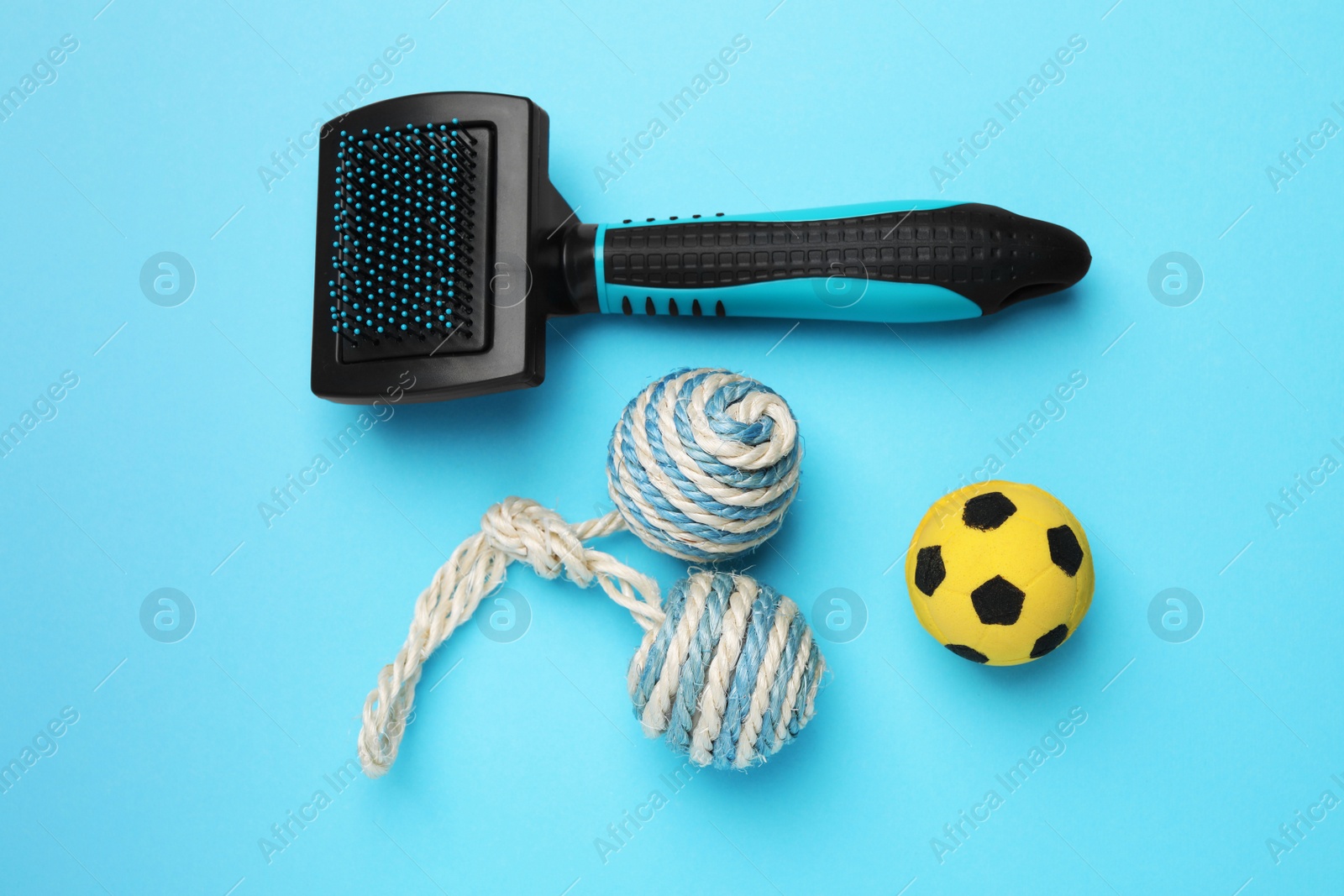 Photo of Pet toys and brush on light blue background, flat lay