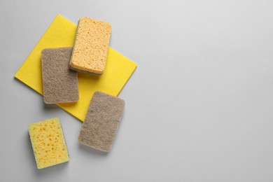 New sponges and rag on light grey background, flat lay. Space for text