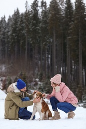 Couple with dog near forest, space for text. Winter vacation