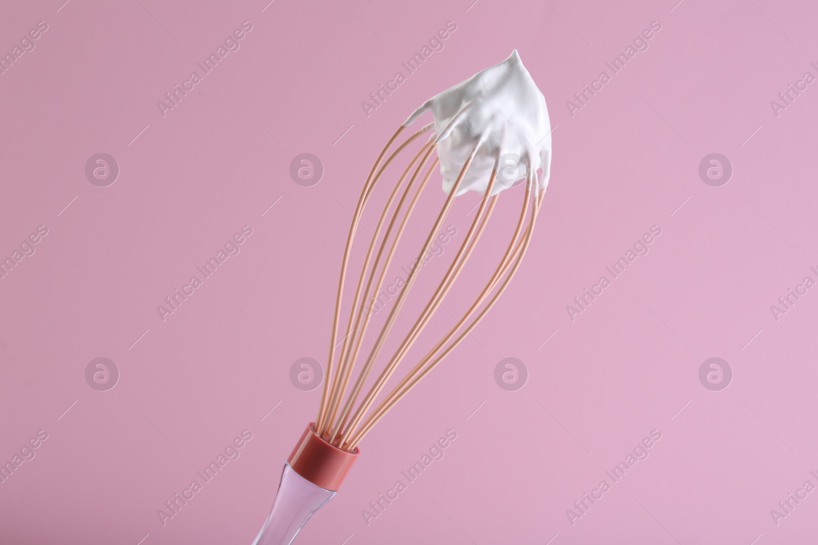 Photo of Whisk with whipped cream on pink background
