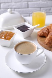 Fresh croissants, jams and coffee on white table. Tasty breakfast