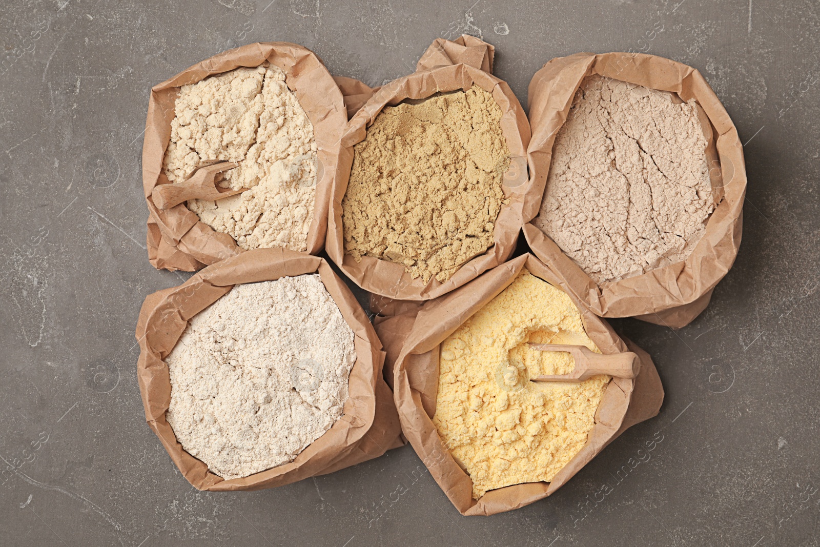 Photo of Paper bags with different types of flour on gray background