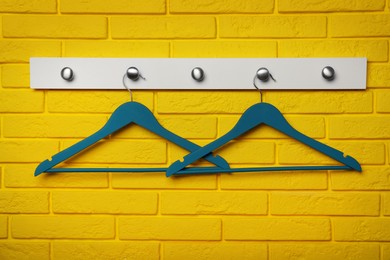 Photo of Rack with clothes hangers on yellow brick wall