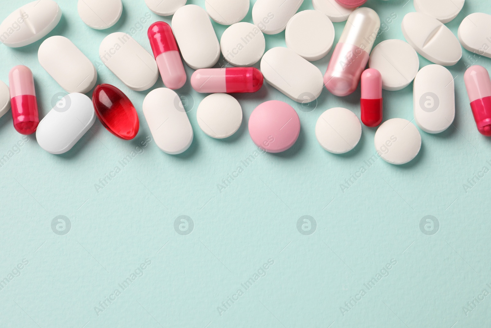 Photo of Many different pills on mint background, flat lay. Space for text