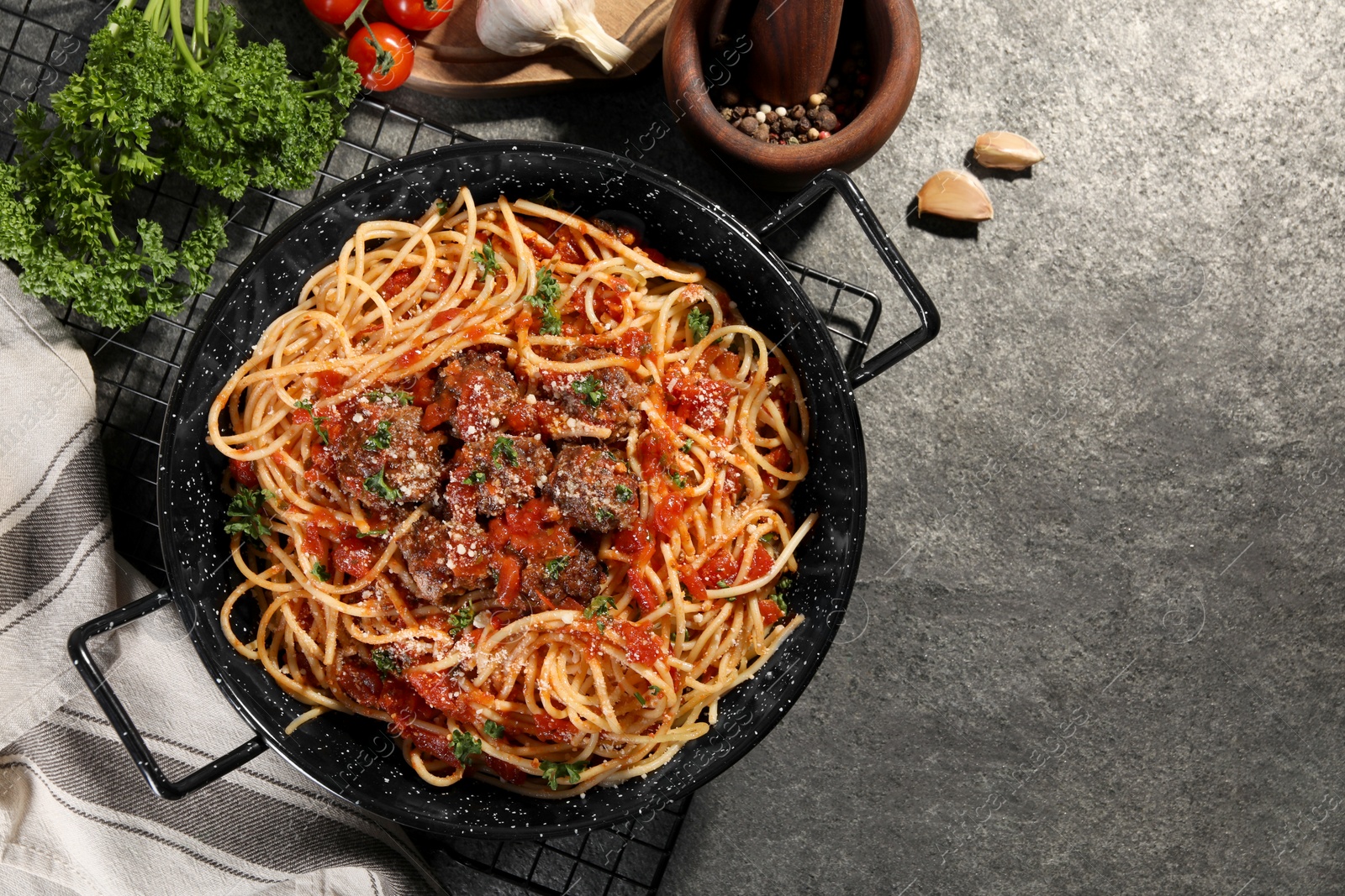 Photo of Delicious pasta with meatballs and tomato sauce near ingredients on grey table, flat lay. Space for text