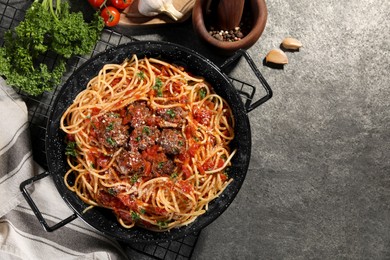 Delicious pasta with meatballs and tomato sauce near ingredients on grey table, flat lay. Space for text