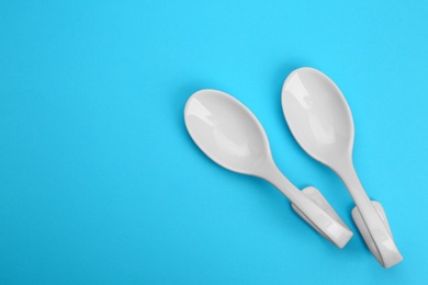 Photo of Clean empty ceramic appetizer spoons on blue background, top view. Space for text