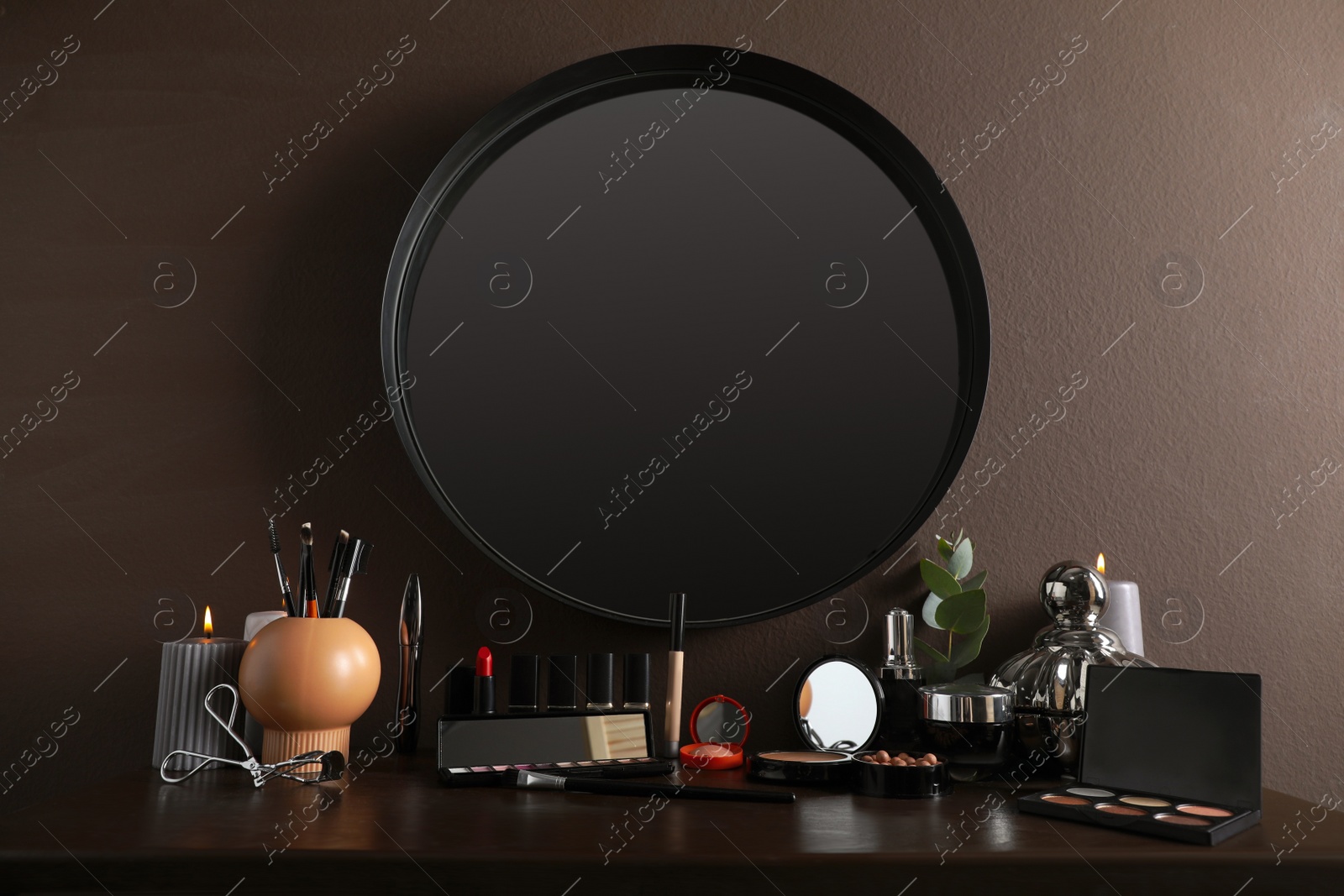 Photo of Stylish round mirror hanging above dressing table with cosmetic products