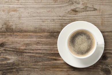 Tasty coffee in cup on wooden table, top view. Space for text