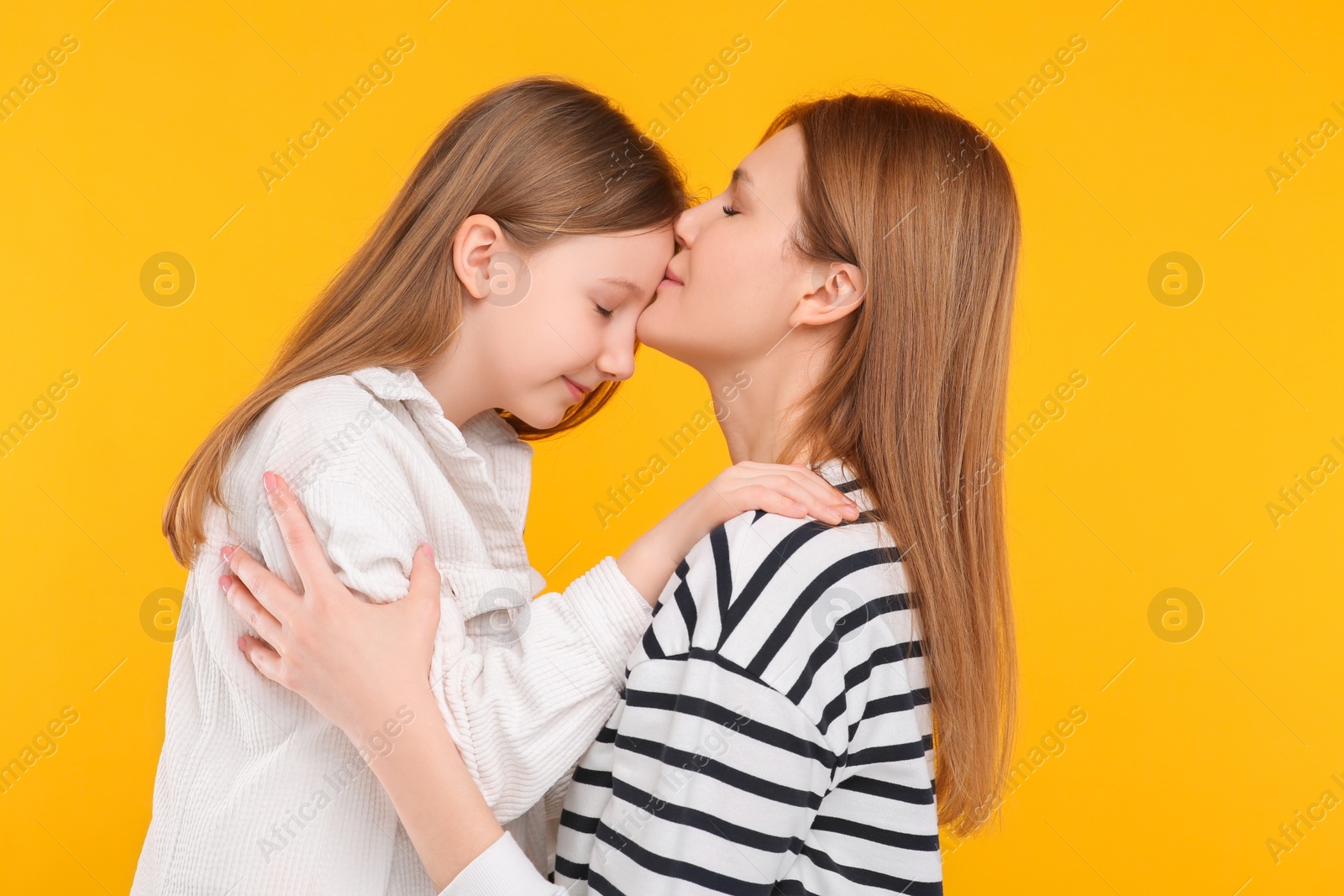 Photo of Portrait of mother and her cute daughter on orange background