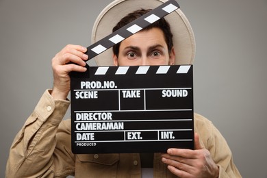 Photo of Emotional actor holding clapperboard on grey background