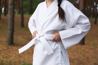 Cute little girl in kimono in forest, closeup. Karate practicing