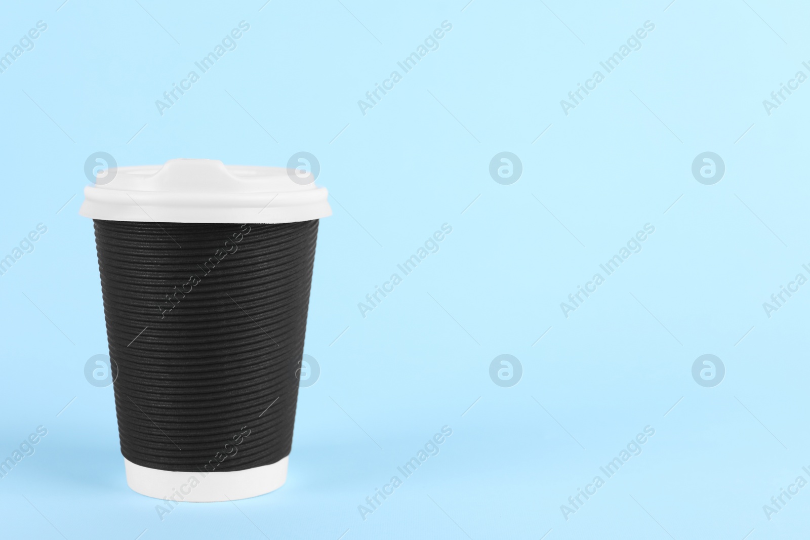 Photo of Black paper cup with plastic lid on light blue background, space for text. Coffee to go