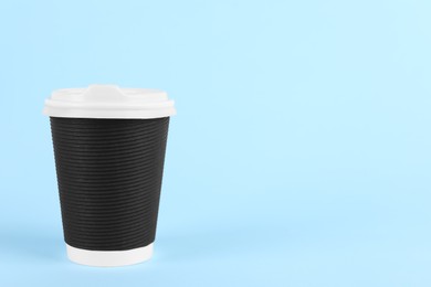 Black paper cup with plastic lid on light blue background, space for text. Coffee to go