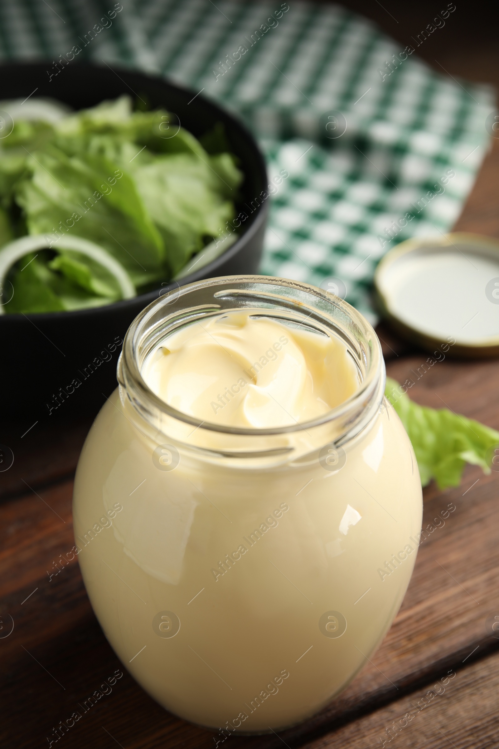 Photo of Jar of delicious mayonnaise and fresh salad on wooden table