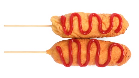 Photo of Delicious deep fried corn dogs with ketchup on white background, top view