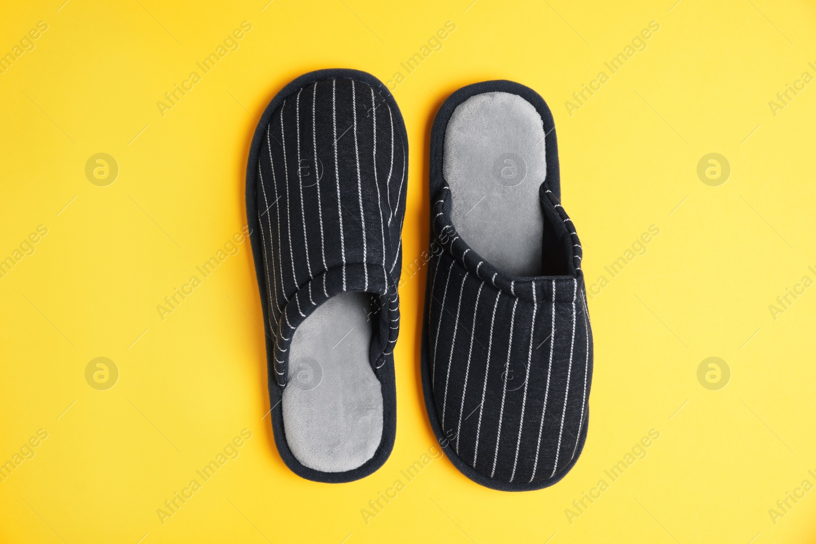 Photo of Pair of stylish slippers on yellow background, top view