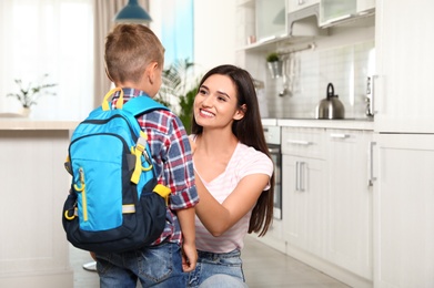 Photo of Happy mother and little child with backpack ready for school in kitchen