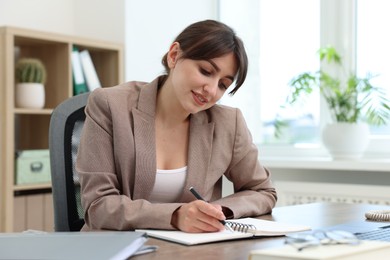 Photo of Smiling secretary working at table in office