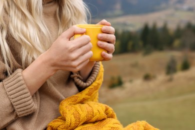 Photo of Young woman with mug of hot drink outdoors, closeup. Space for text