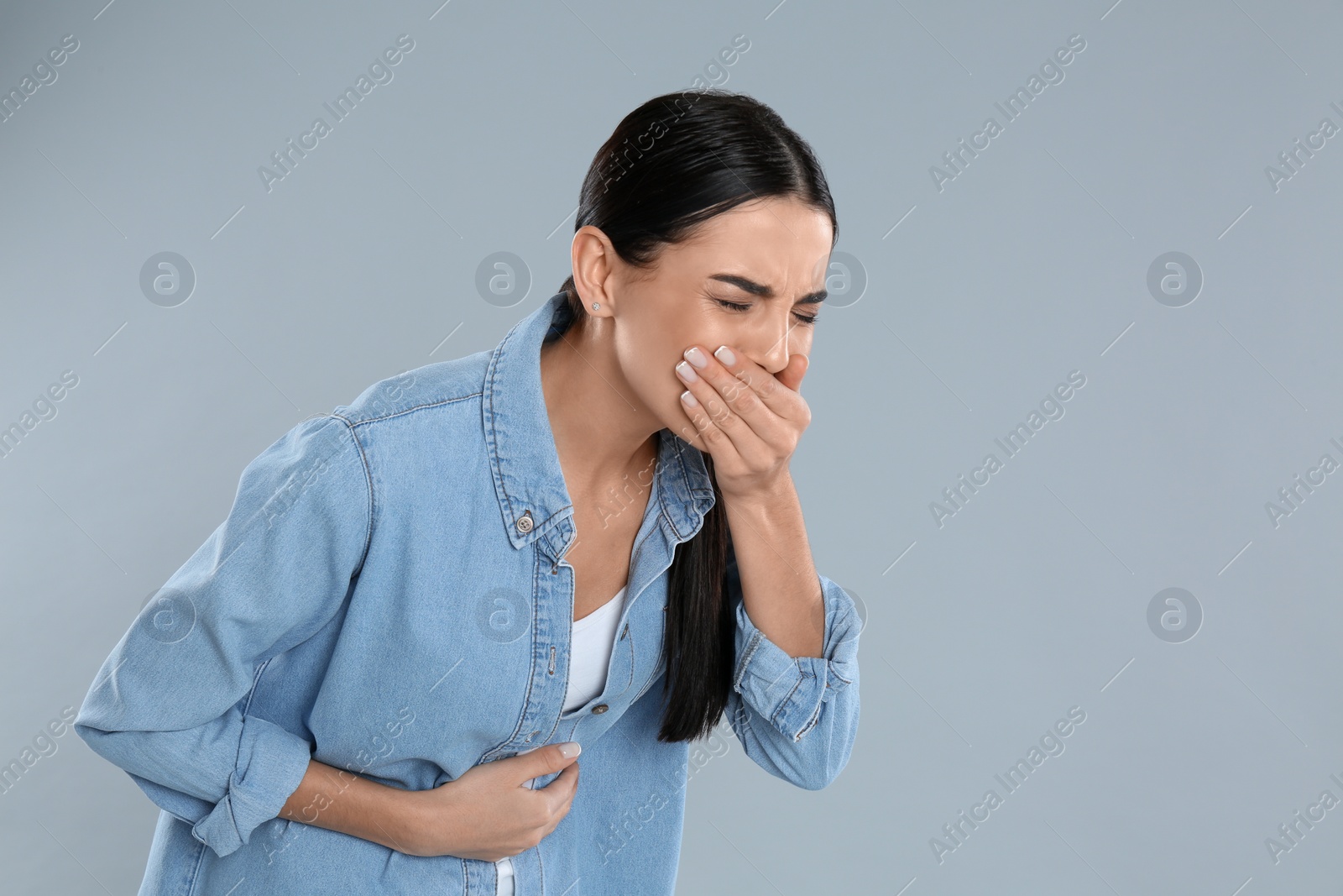 Photo of Woman suffering from stomach ache and nausea on grey background, space for text. Food poisoning