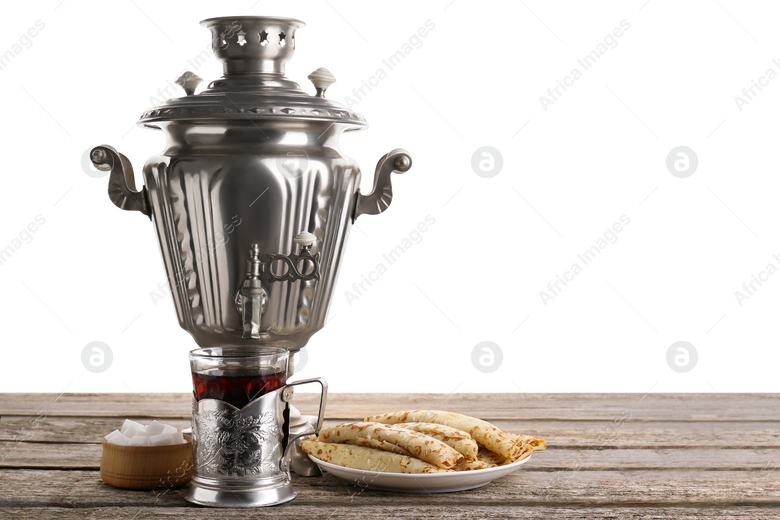 Photo of Vintage samovar, cup of hot drink and snacks on wooden table against white background, space for text. Traditional Russian tea ceremony