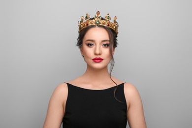Photo of Beautiful young woman wearing luxurious crown on light grey background
