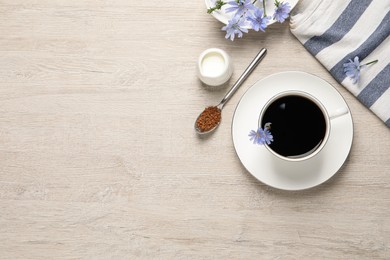 Photo of Cup of delicious chicory drink, granules and flowers on light wooden table, flat lay. Space for text