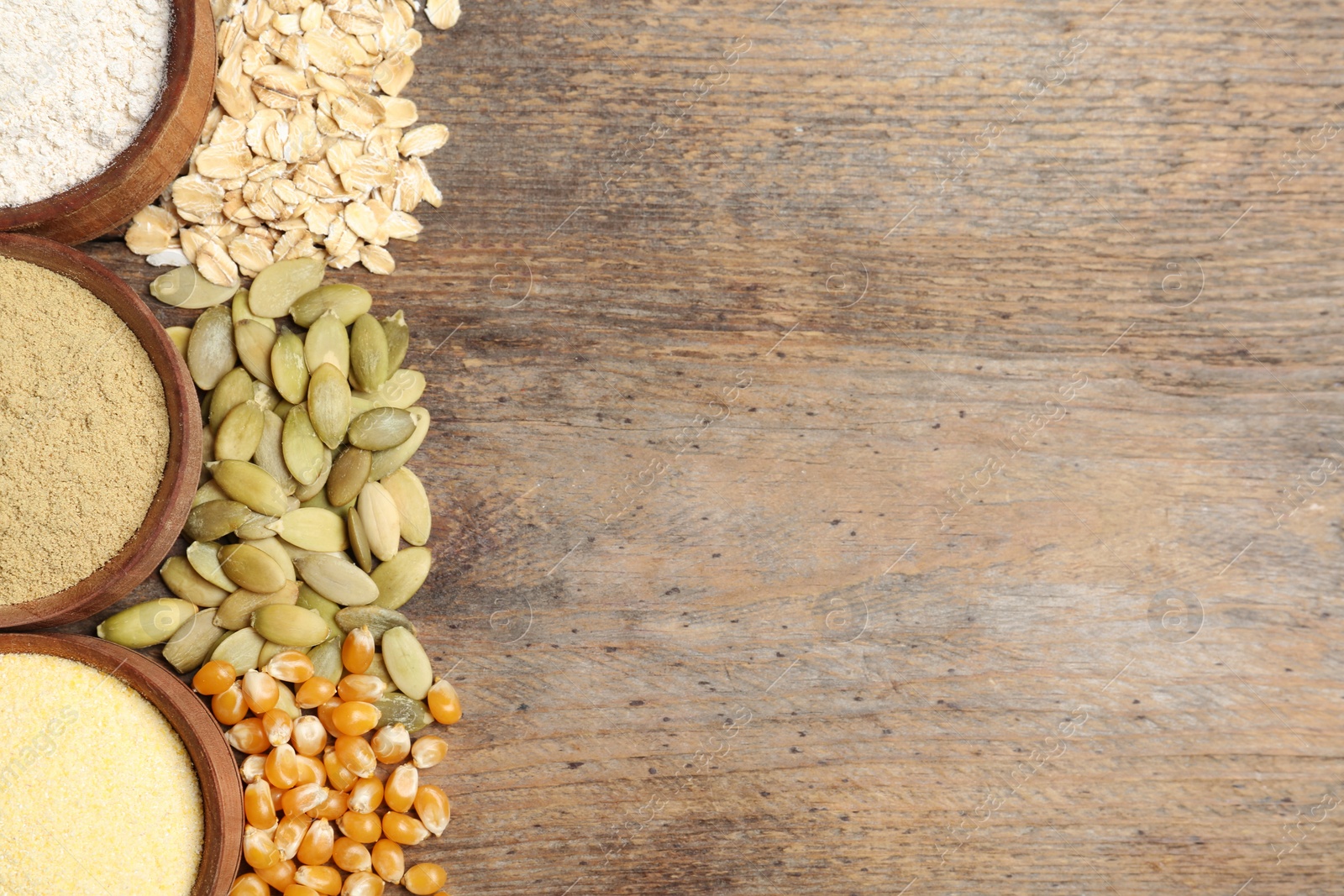 Photo of Flat lay composition with different types of flour and seeds on wooden background. Space for text