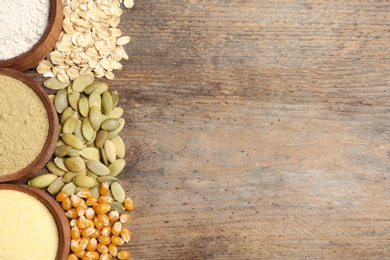 Flat lay composition with different types of flour and seeds on wooden background. Space for text