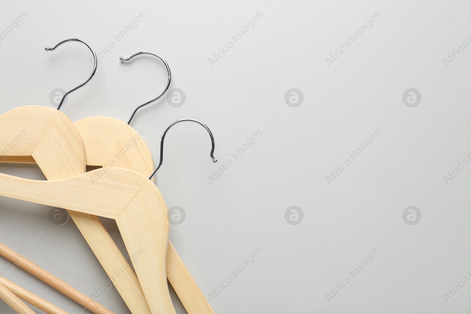 Photo of Wooden hangers on light gray background, top view. Space for text