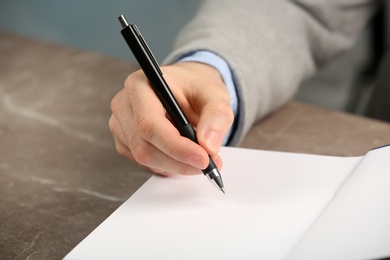 Photo of Writer signing autograph in book at table, closeup