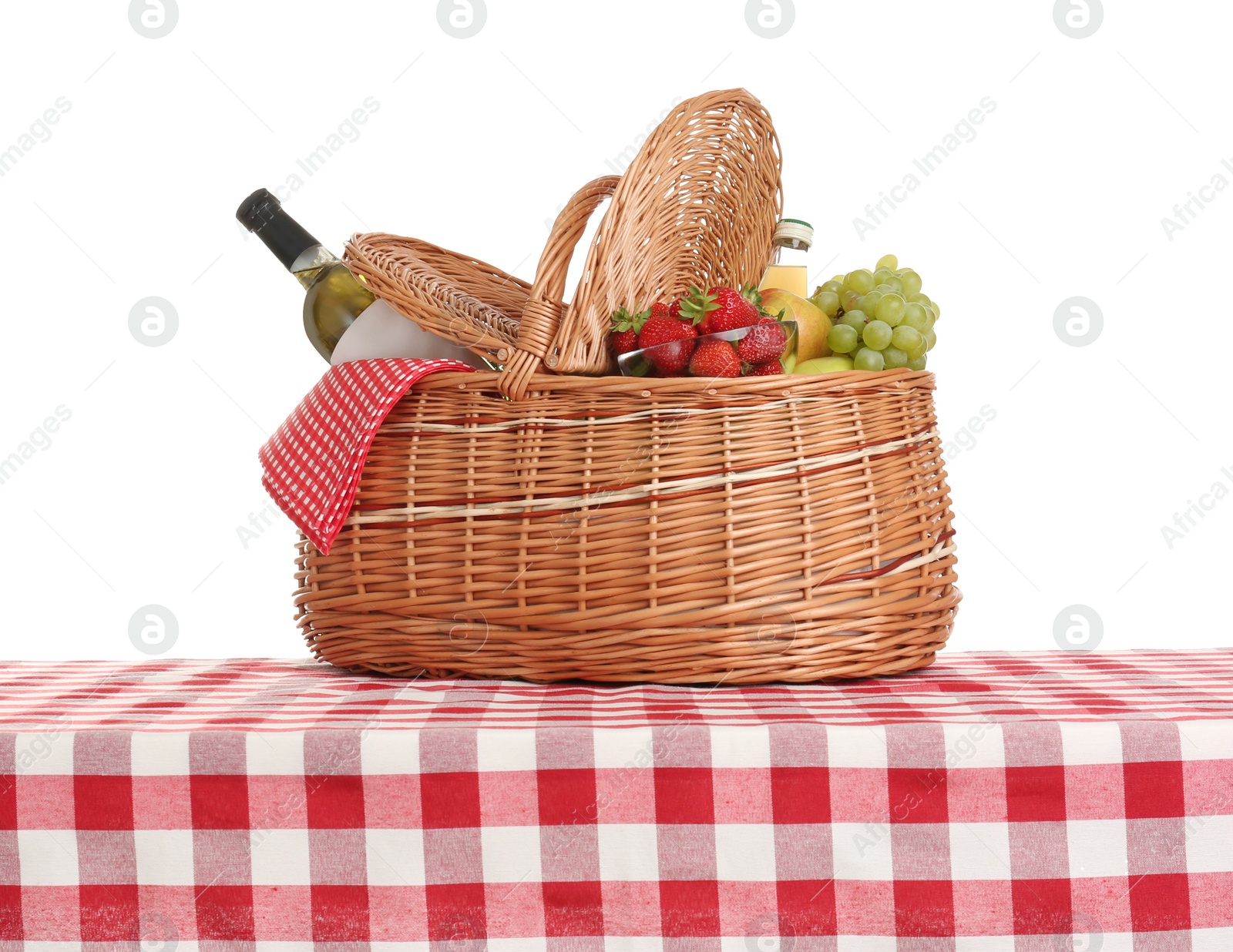 Photo of Picnic basket with wine and fruits on tablecloth against white background