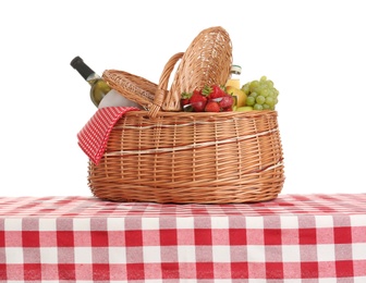 Photo of Picnic basket with wine and fruits on tablecloth against white background