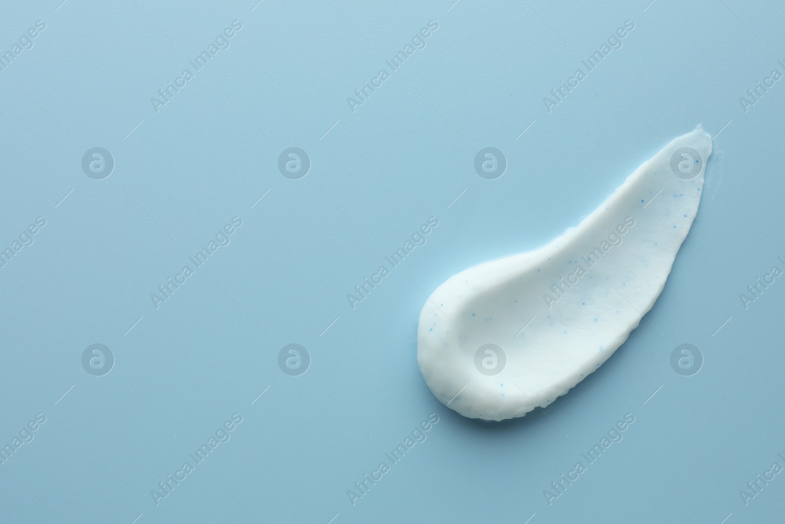 Photo of Sample of face scrub on light blue background, top view. Space for text