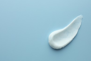 Sample of face scrub on light blue background, top view. Space for text