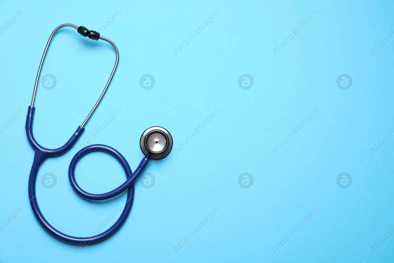 Photo of Stethoscope on light blue background, top view. Space for text