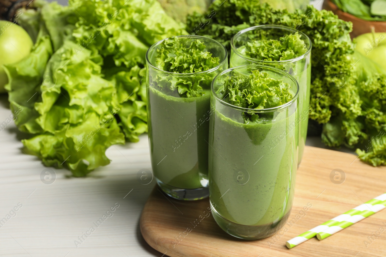 Photo of Green smoothie of lettuce leaves in glasses on white wooden table