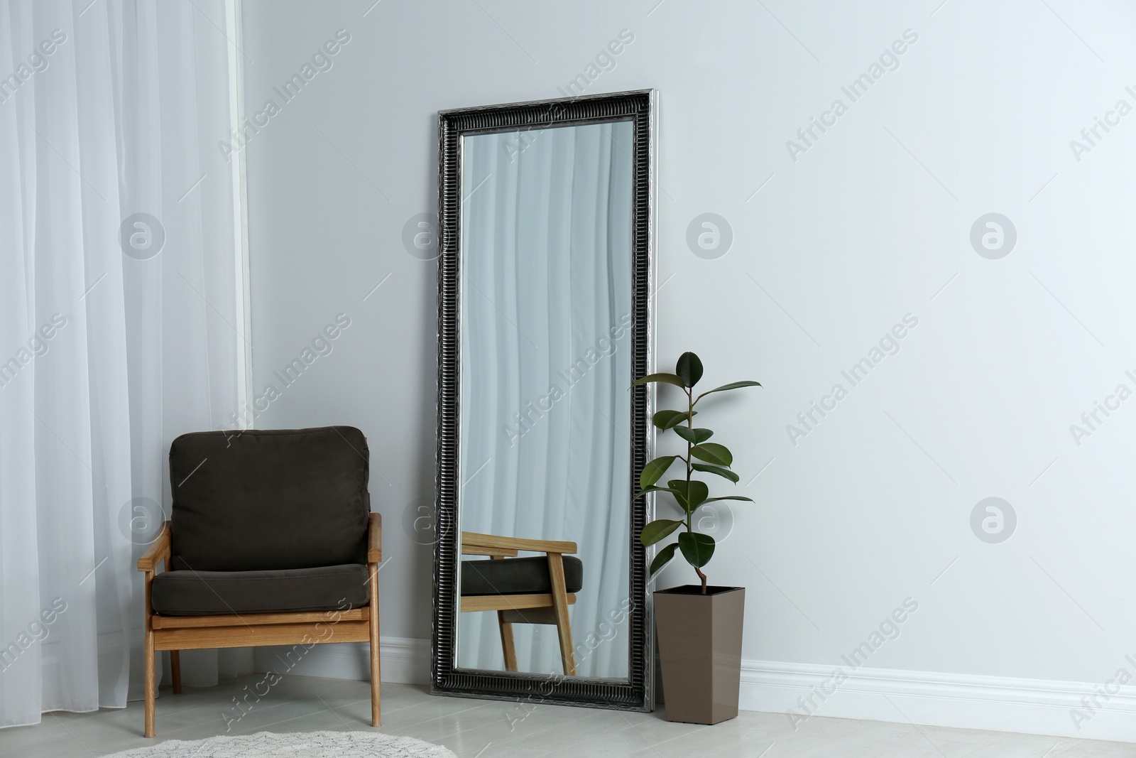 Photo of Modern interior with large mirror and comfortable armchair near white wall