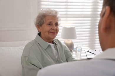 Photo of Caregiver talking to senior woman in living room. Home health care service